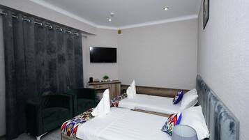 A hotel room with two beds, a desk, a chair, a TV, and a window with curtains.