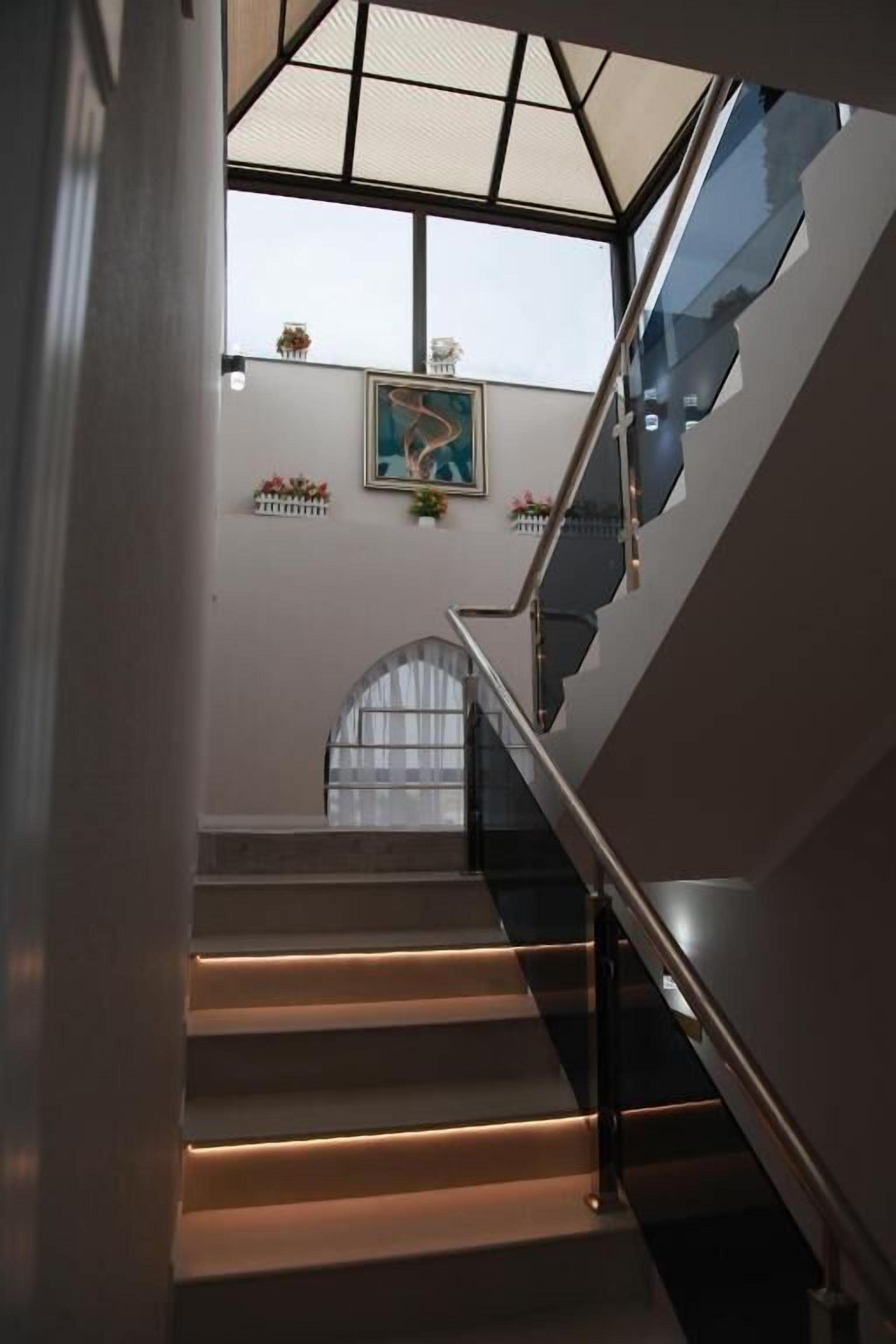 Una escalera con barandilla de cristal que lleva a un rellano con tragaluz.