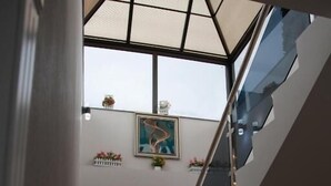 Una escalera con barandilla de cristal que lleva a un rellano con tragaluz.
