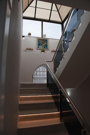 A staircase with a glass balustrade leading to a landing with a skylight. - Samarqand Darvoza (Bukhara)