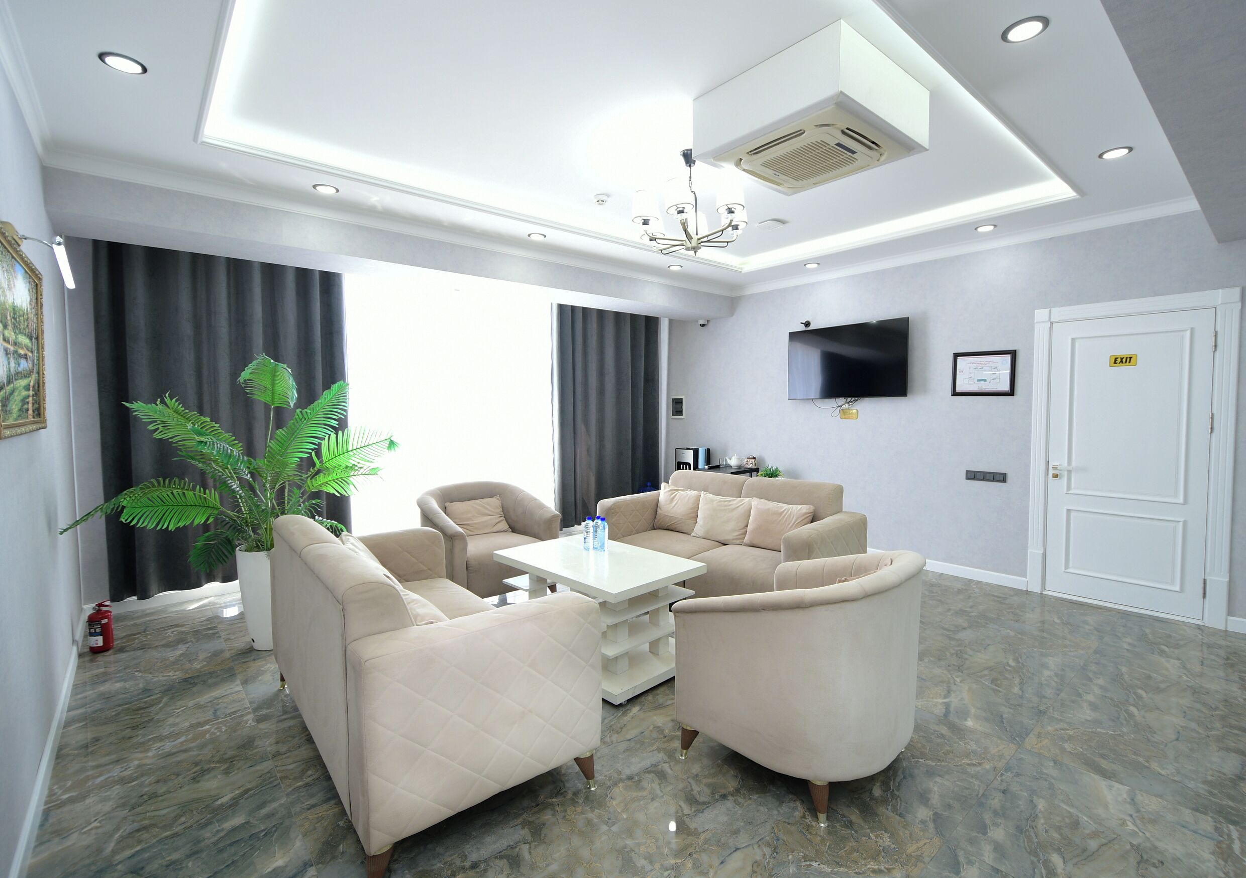 A modern living room with a sofa set, a coffee table, a flat-screen TV, and a large window with curtains.