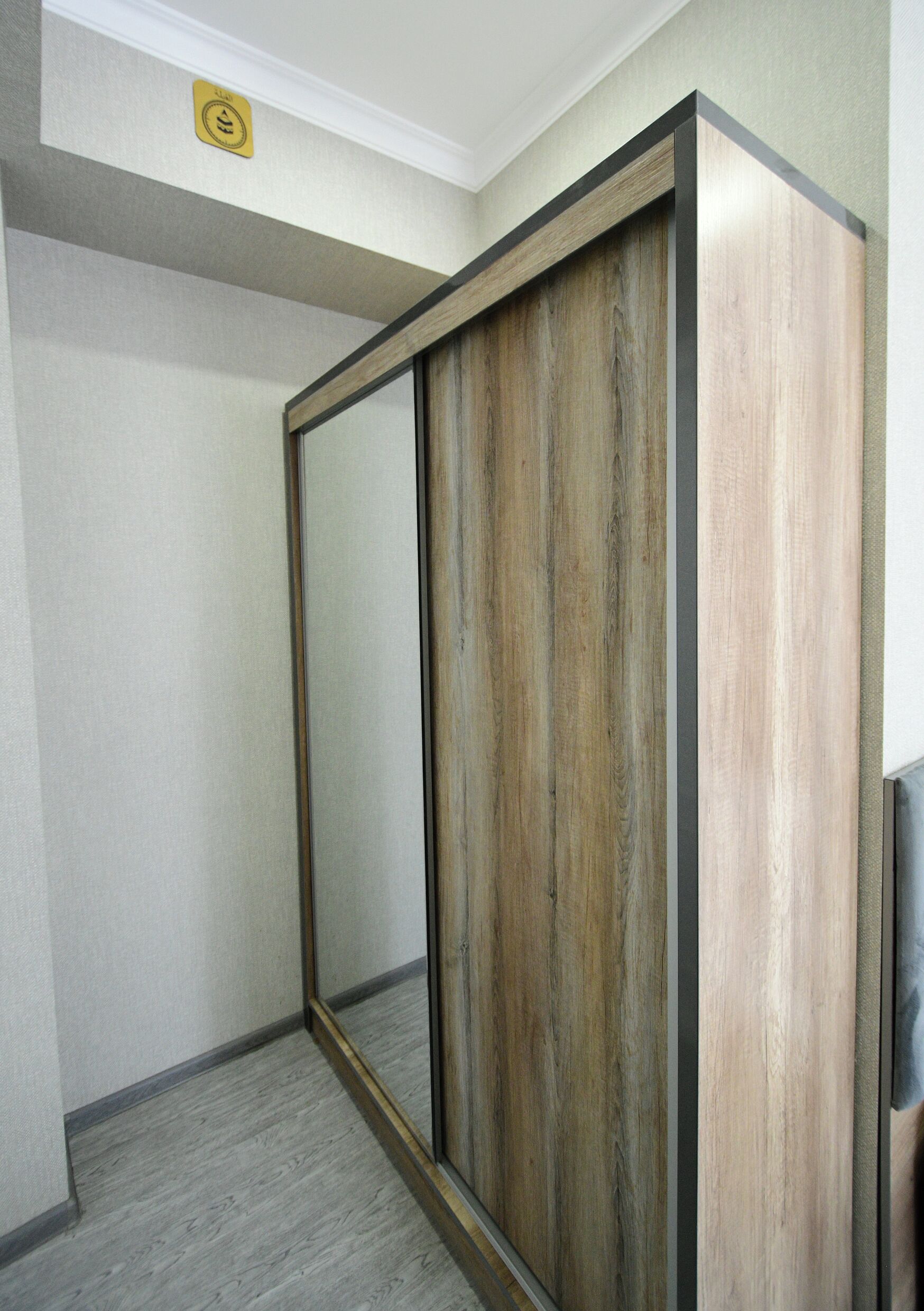 A room with a large mirror, a wooden wardrobe, and a grey floor.