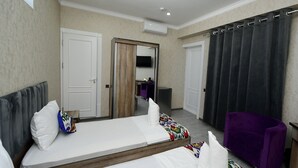 Una habitación de hotel con cama, una silla, armario y espejo.