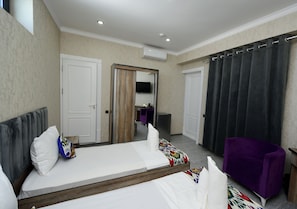 A hotel room with a bed, a chair, a wardrobe, and a mirror. - Samarqand Darvoza (Bukhara)