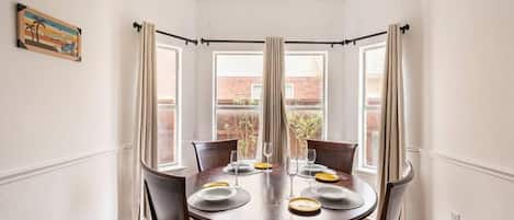 Une salle à manger avec une table ronde, quatre chaises et un lustre.