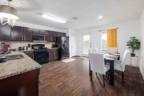 A modern kitchen with dark wood cabinets, stainless steel appliances, and a granite countertop. - Kitchen Foosball Fenced Yard Parking (Kyle)