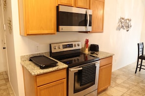 Una cocina con armarios de madera, un microondas de acero inoxidable, una estufa y un tostador.