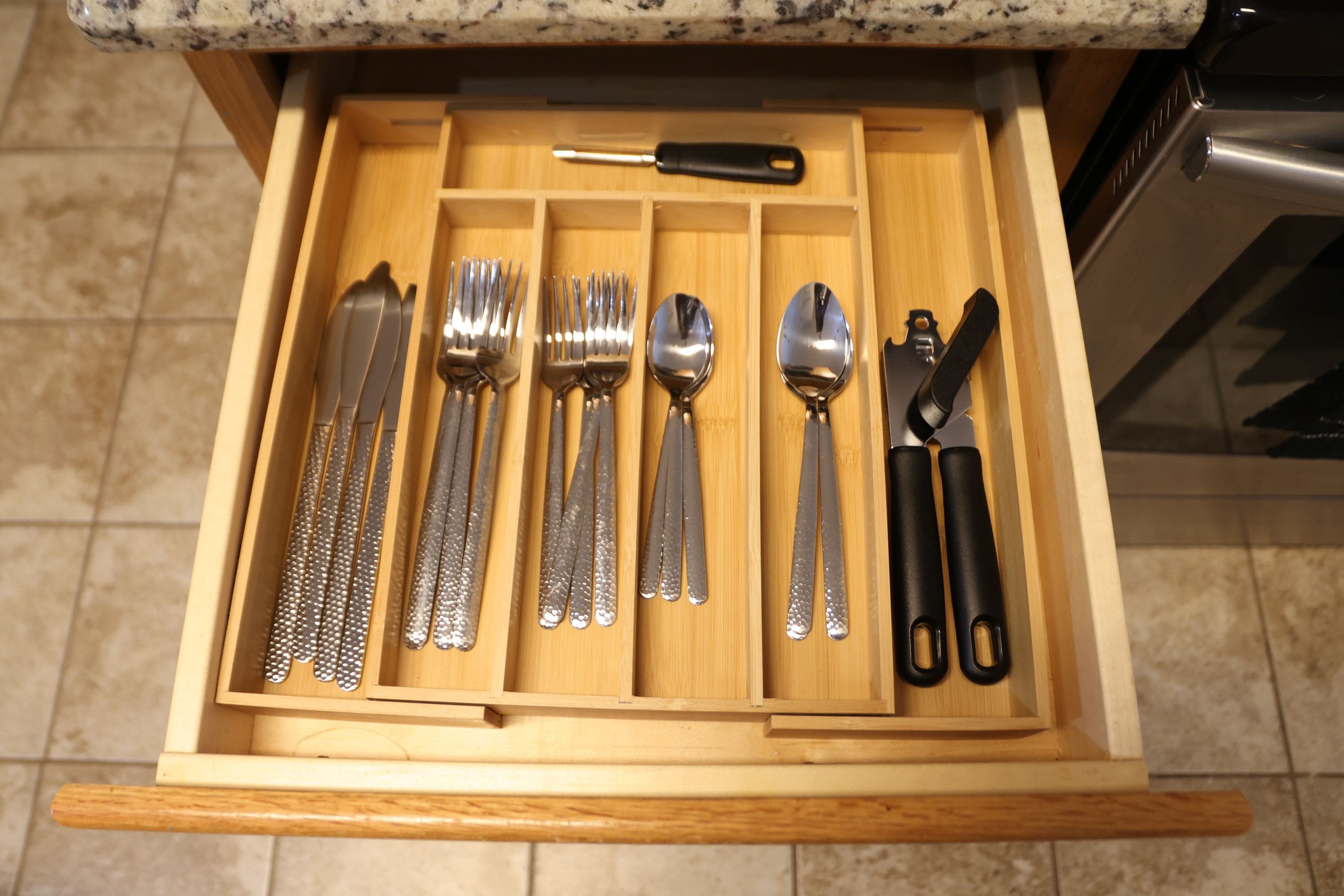 A drawer with various utensils including forks, spoons, and a knife.