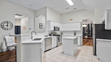 A modern kitchen with white cabinetry, a stainless steel sink, and a tiled floor.