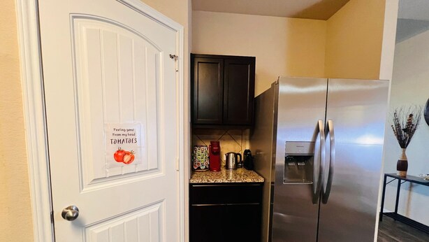 Una cocina con un refrigerador de acero inoxidable, una cafetera y un dispensador de agua.