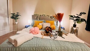 Un dormitorio ordenado con una cama, mesitas de noche y dos plantas en macetas.