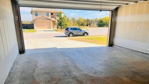 Un garaje con piso de concreto y vista a una calle residencial.