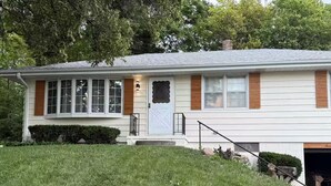 A two-story house with a front porch, a garage, and a well-maintained lawn. - Midtown Omaha Near Everything! No Cleaning Fee! (Omaha)
