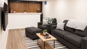 A modern living room with a sofa, ottoman, and coffee table. - Midtown Omaha Near Everything! No Cleaning Fee! (Omaha)
