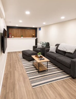 A modern living room with a sofa, ottoman, and coffee table. - Midtown Omaha Near Everything! No Cleaning Fee! (Omaha)