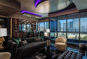 Ein modernes Wohnzimmer mit einem Ledersofa, einem runden Couchtisch und Blick auf die Stadt durch große Fenster.
