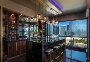 A modern bar area with a marble countertop, hanging spherical light fixtures, and a view of the cityscape through large windows. - This 2 bedroom, 2.5 bath penthouse is perfect for your next Las Vegas getaway! (Las Vegas)