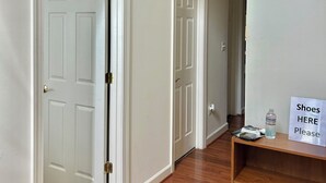 A hallway with white doors, a wooden floor, and a sign indicating a shoe storage area.