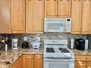 A kitchen with wooden cabinets, a microwave, a stove, a coffee maker, and a toaster.