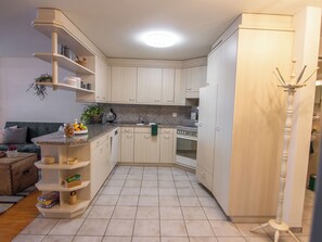 Cocina compacta con horno integrado, un lavamanos y una zona de comedor con sofá y mesa de centro.