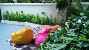 An outdoor seating area with a yellow bean bag and a pink chair on a patterned rug. - Aura Retreat Boutique Hotel Hanoi (Hanoi)