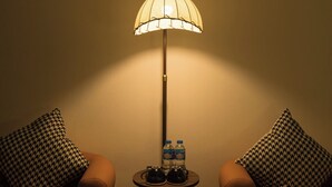 Una habitación con dos sillones, una mesita con lámpara y una botella de agua.