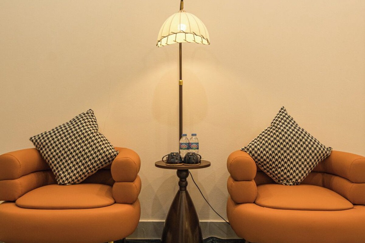 A room with two orange armchairs, a floor lamp, and a small table with water bottles.
