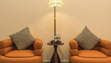 A room with two orange armchairs, a floor lamp, and a small table with water bottles.