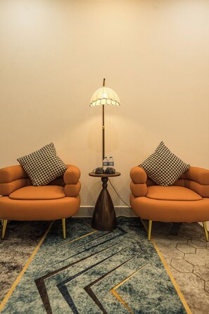 A room with two orange armchairs, a floor lamp, and a small table with water bottles. - Aura Retreat Boutique Hotel Hanoi (Hanoi)