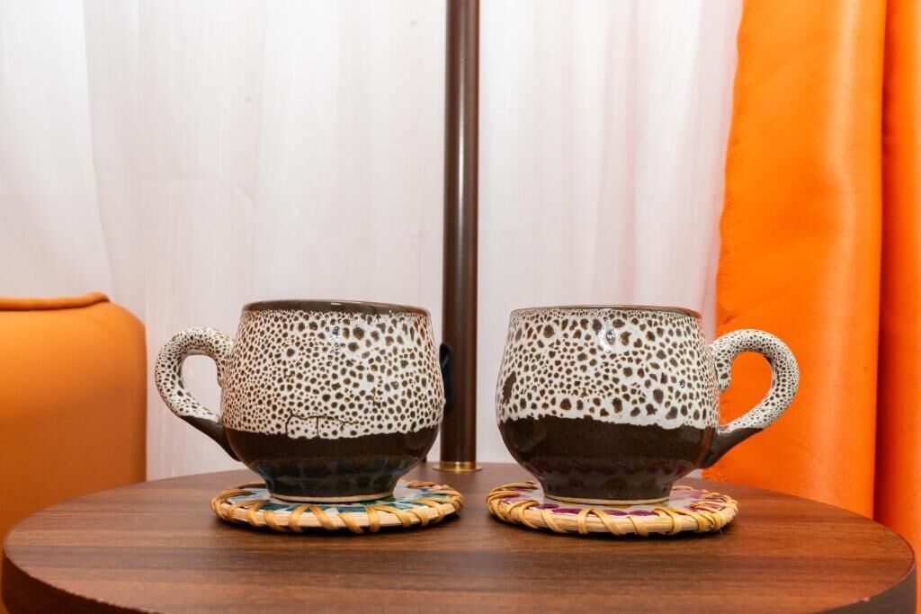Dos tazas de cerámica con diseños moteados sobre una mesa redonda de madera.