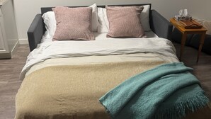 A bed with a beige blanket, a teal throw, and two pillows.
