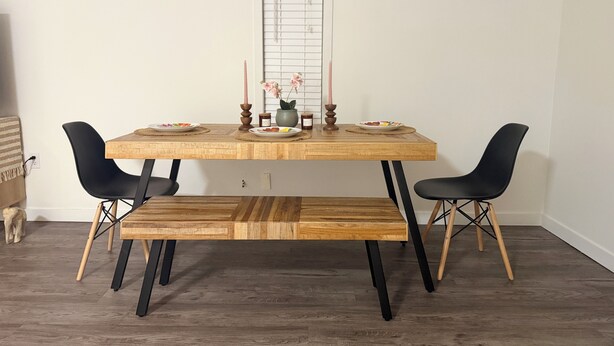 A dining table with two chairs, a bench, and candles.