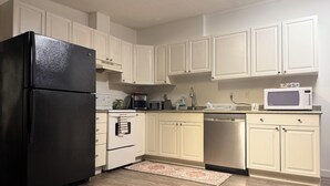 A kitchen with white cabinets, a black refrigerator, a microwave, a dishwasher, and a coffee maker.