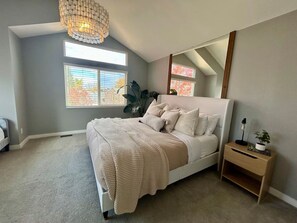 Ein Schlafzimmer mit Bett, Nachttisch, Spiegel und Fenster.