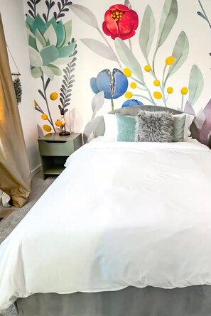 Una camera da letto con un letto, un comodino, una lampada e un affresco.