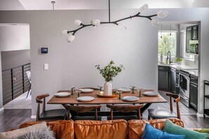 Un'area pranzo moderna con un tavolo in legno apparecchiato per quattro persone, circondata da divani in pelle.