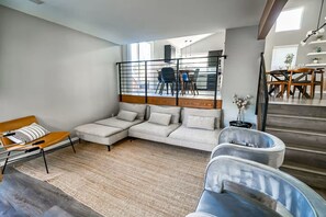 Ein modernes Wohnzimmer mit einem Ecksofa, einer kleinen Holzbank und einem Metallstuhl.