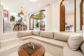 Un saló modern amb un sofà seccional en forma de L, una taula de centre de fusta i una zona de menjador amb taula i cadires.