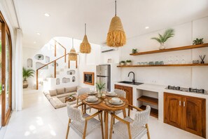 Cuina moderna amb zona de menjador, armaris de fusta i una escala que condueix a un nivell superior.