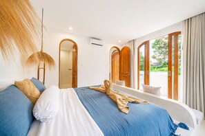 Un dormitori modern amb un llit gran, una làmpada penjant i vista a l'exterior a través d'una porta de vidre.