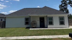 A single-story house with a dark roof, light siding, and a front porch with a chair. - 3BR home w/ AC, parking & W/D near Galleria/ Downtown (Houston)