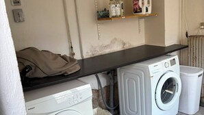 A laundry area with two washing machines, a shelf with detergent bottles, and a black countertop. - Comfortable and centrally located home in Odense (Odense)