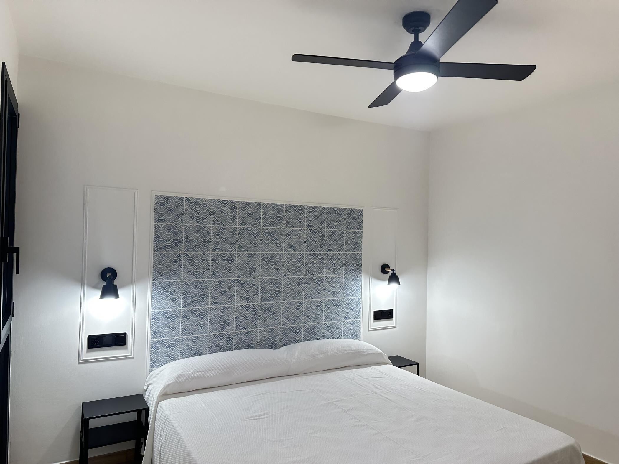 Un dormitorio con cama, ventilador de techo y luces empotradas.