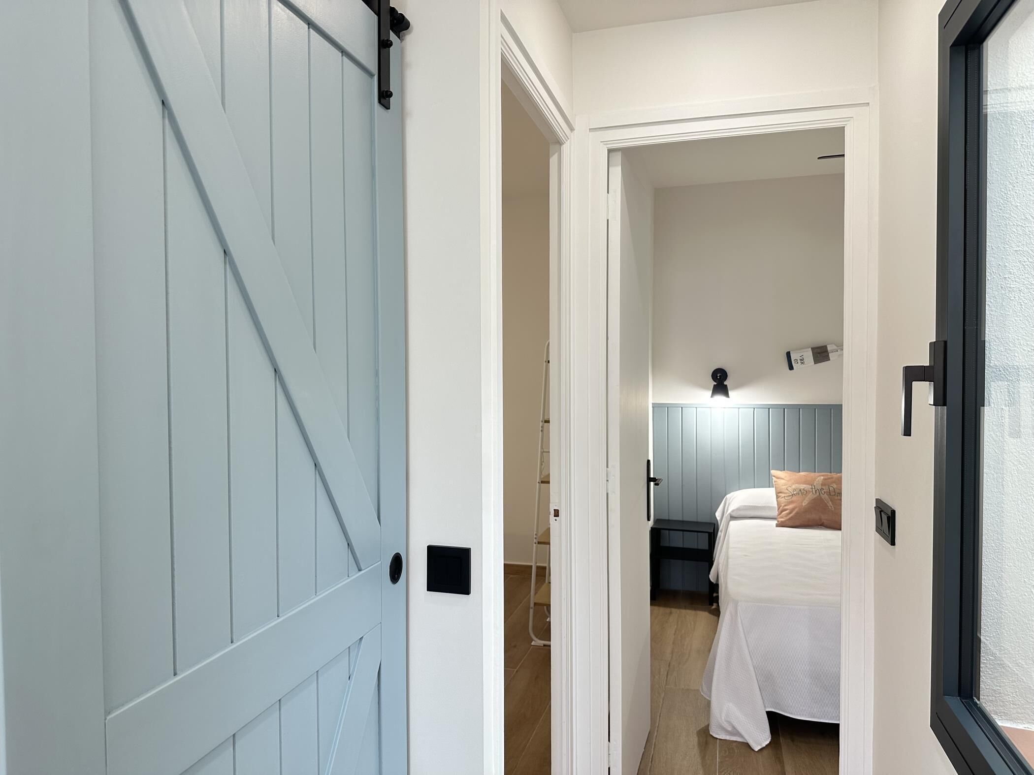 A bedroom with a bed, a nightstand, and a wall-mounted light fixture.