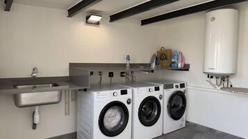 A laundry room with two front-loading washing machines, a sink, and a water heater.