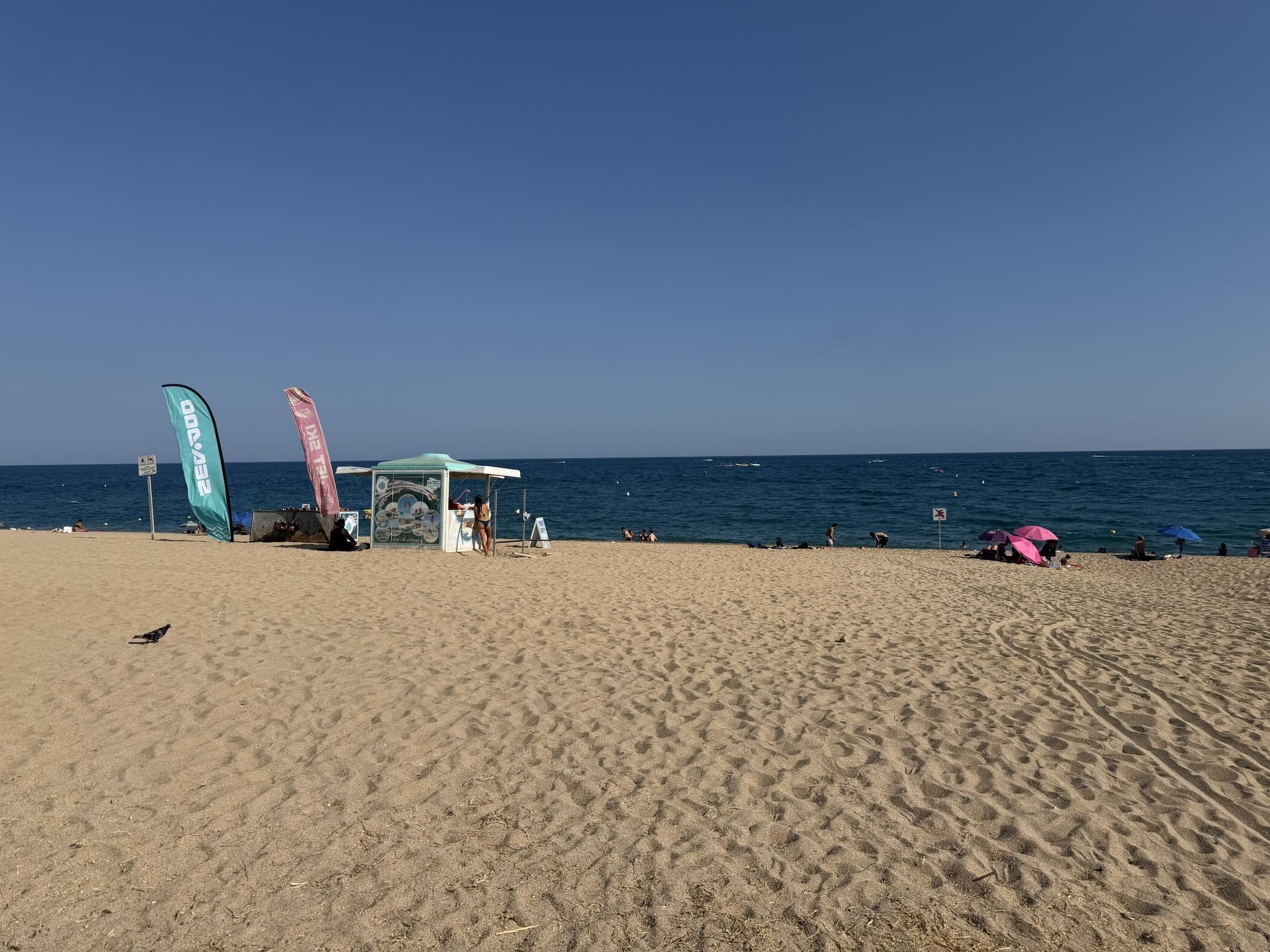 A beach with a tent, flags, and people.
