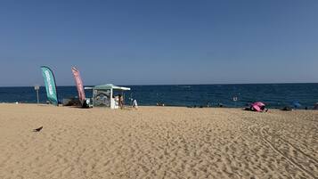 A beach with a tent, flags, and people.