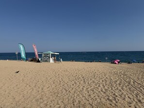 A beach with a tent, flags, and people.