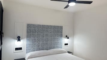 Een slaapkamer met een bed, een plafondventilator en wandlampen.
