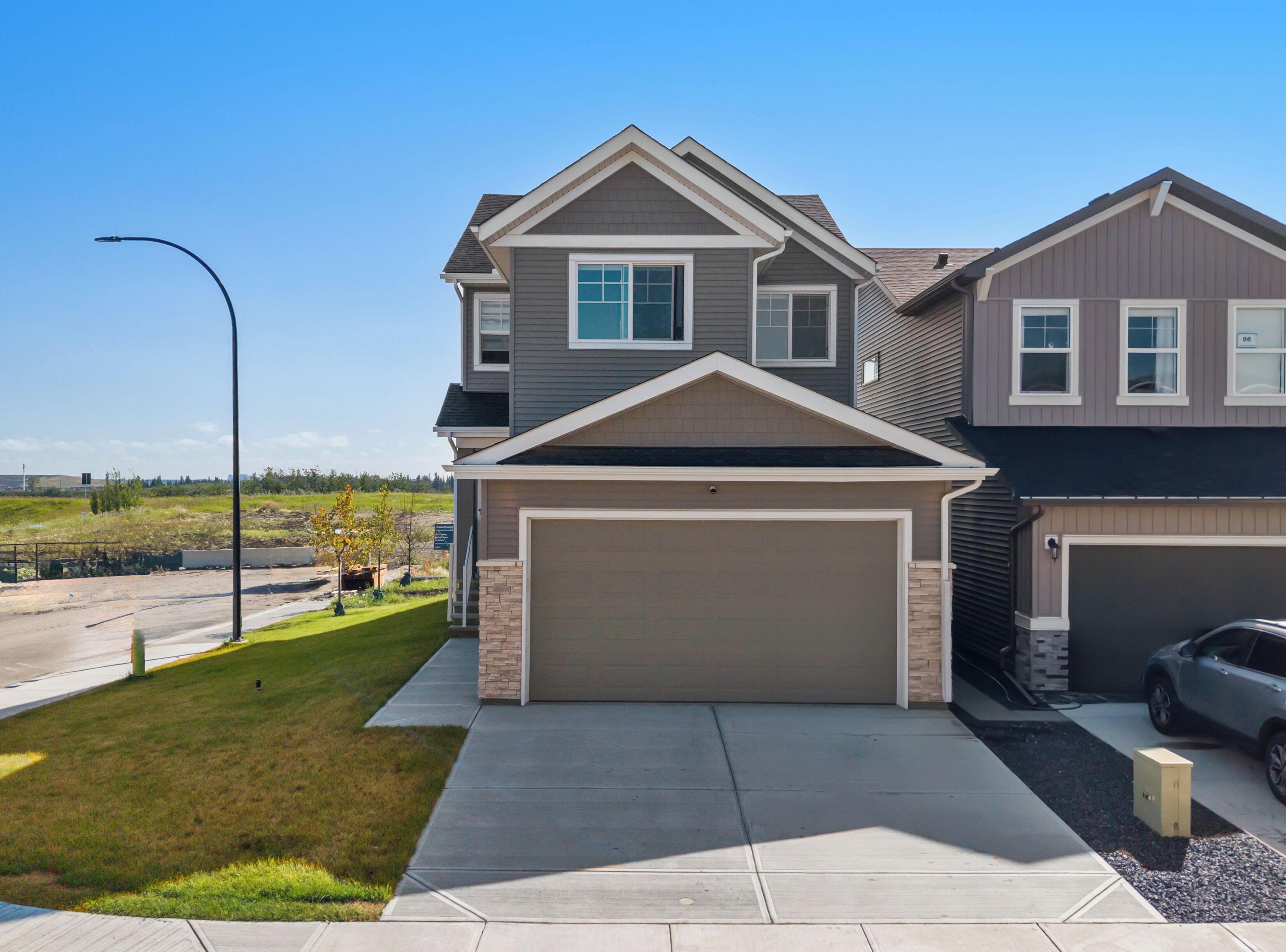 A two-story residential building with a garage, a driveway, and a street lamp.